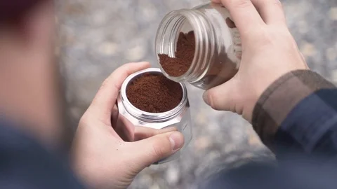 Putting Coffee in an old Espresso maker by the fire Stock-Footage 120190057