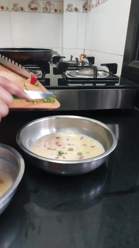 Putting cut green chillies from vegetable cutting board into bowl with egg .. Stock Footage 235484592