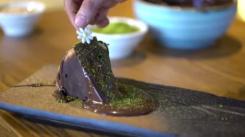 Putting a daisy on a slice of chocolate cake Stock Footage 167588857