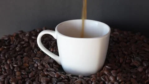 Putting dark coffee on white cup of coffee on turn table with coffee grounds, on Stock Footage 243295536