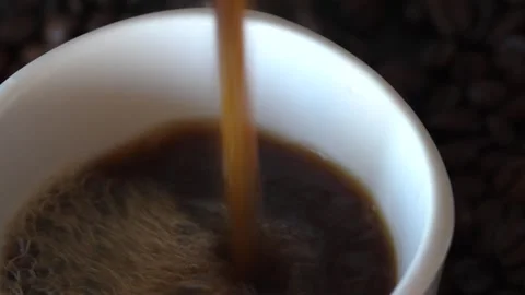 Putting dark coffee on white cup of coffee on turn table with coffee grounds, on Video stock 243295609