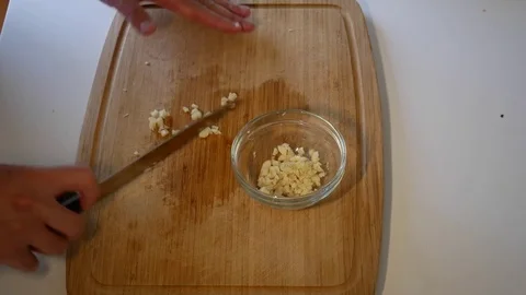 Putting Diced Garlic with a kitchen knife into a glass bowl Stock Footage 79287022