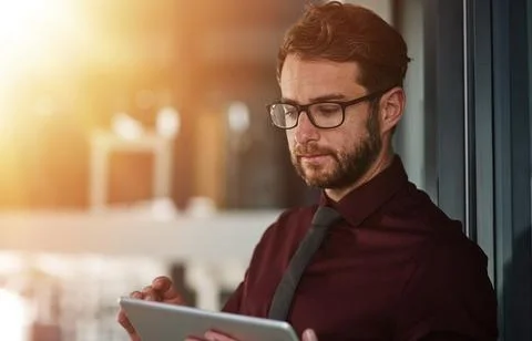 Putting digital tech to work. a young businessman using a digital tablet in a Stock Photos
