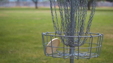 Putting a Disc in a Frisbee Golf Basket Stock Footage