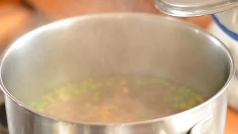 Putting up dish cover from Bubbling vegetble soup, inside a metal pot. Stock Footage 73140266