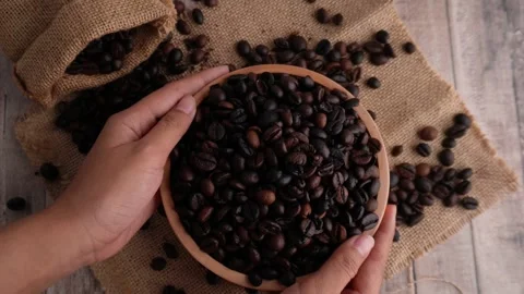 Putting down and picking up by hand a wooden bowl of roasted coffee beans Stock Footage 273277994