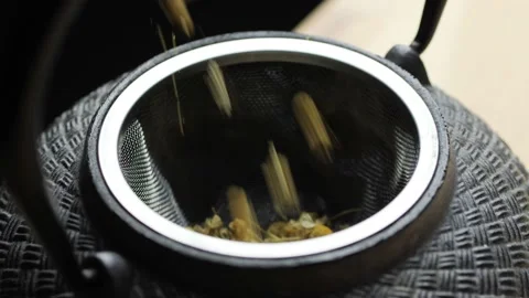 Putting dried chamomile into a cast iron tea pot Stock Footage 144690370