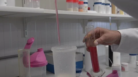 Putting a drop of red liquid in a plastic container with a pipette or dropper. Stock Footage 91906680