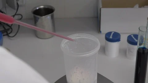 Putting a drop of red liquid in a plastic container on a scale  with a pipette Stock Footage 91906744
