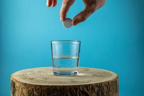 Putting effervescent pill into glass full of water 写真素材