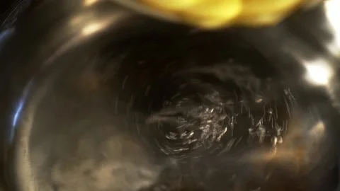 Putting egg into the boiling water to make a poached egg with liquid yolk. Macro Stock Footage 133338937