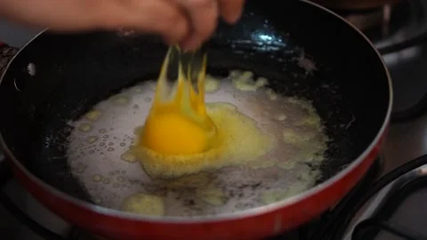 Putting an egg in the frying pan with melted butter. Stock Footage 141964536