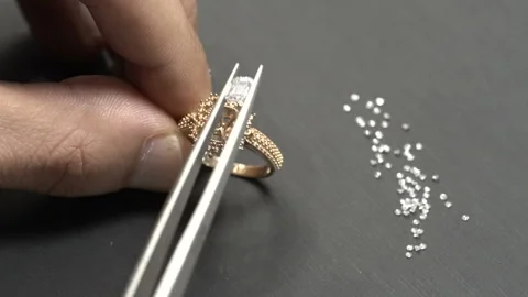 Putting the emerald cut diamond on the roze gold solitaire ring. Stock Footage 139726809