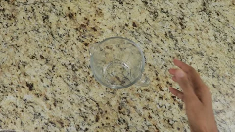 Putting empty glass measuring cup on a table, top down view Stock Footage 266231526