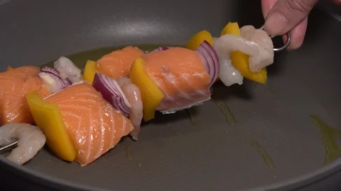 Putting fish spits into a pan Stock Footage 126272839
