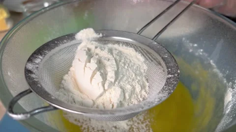 Putting flour on a sieve to sift it when making dough. Stock Footage 234287823