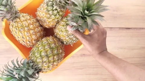 Putting fresh Pineapple in bowl on table 스톡 동영상 150156470