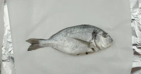 Putting a fresh sea bream onto a baking paper Stock Footage 134627081