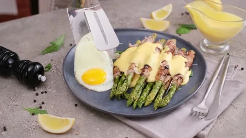 Putting fried egg into plate with freshly cooked asparagus wrapped with bacon Vídeos de archivo 218222640