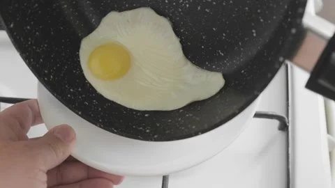 Putting fried eggs from frying pan on plate Stock-Footage 295038265