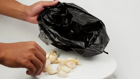 Putting Garlic Into a Black Plastic Bag Stock Footage 327848059