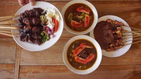 Putting goat satay on the dining table containing chicken satay and tongseng Stock Footage 270347260