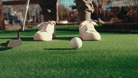 Putting Green Slow Motion White Sneakers Putter Ball Urban Setting Bright Day Video stock 334490346
