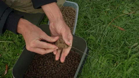 Putting ground bait into a method feeder basket Stock Footage 228601141