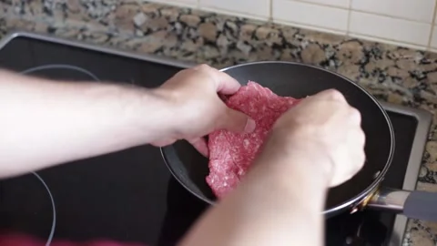 Putting a hamburger in a frying pan Stock Footage 139262392