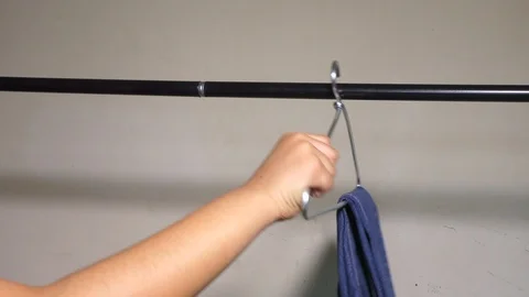 Putting the hangers with clothes on the rod Stock Footage 128199149