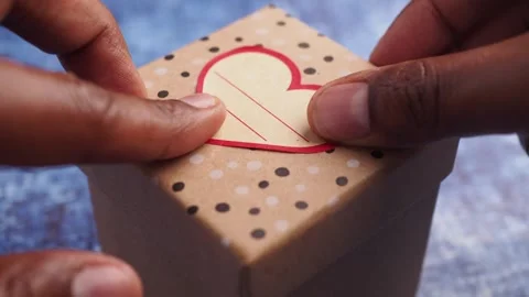 Putting heart shape sticker on a wrapper gift , Stock Footage 312085283