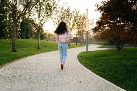 Putting her hands in the back pockets of jeans dark-haired girl goes away on the Stock Photos