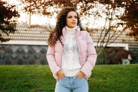 Putting her hands in the front pockets of jeans a beautiful girl dressed in the Stock Photos