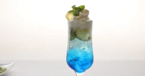 Putting herbal leaf and lemon slice on curacao cream soda with ice cream Video stock 136726243