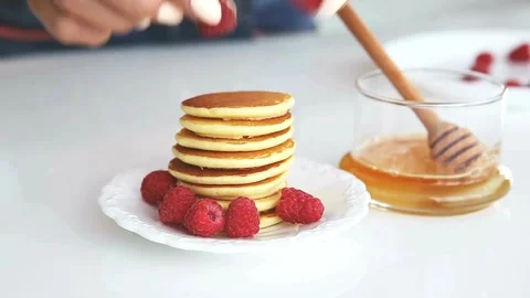 Putting honey or jam on pancakes with raspberries. tasty pancakes with berries. Stock-Footage 336589372