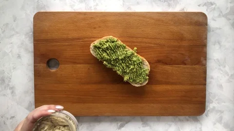 Putting hummus on avocado bruschetta Stock Footage 129180904