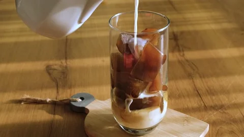 Putting ice cubes made from coffee in a glass and pouring milk over it. Vídeo Stock 157829871