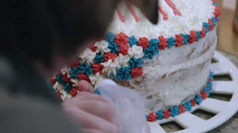 Putting icing on a red white and blue cake Stock Footage 64894074