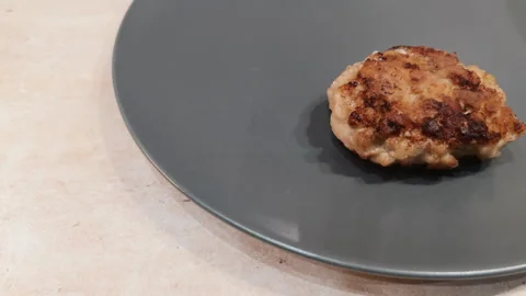 Putting just made fried cutlets on dark grey plate. Serving meat patty cakes in Stock Footage 273002792