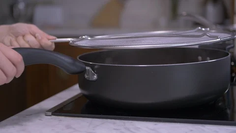Putting Mesh Splatter Guard Onto Hot Pan Video stock 97705741
