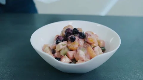 Putting mint leaves into a fruit salad bowl. Making delicious healthy sweet Video stock 136674492