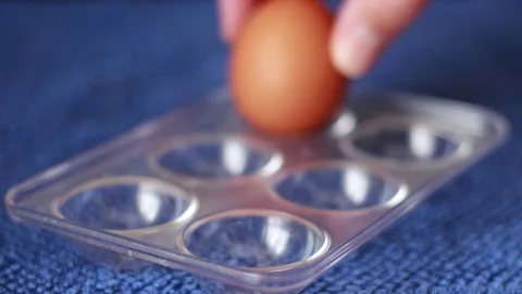Putting one white among yellow eggs in a box 스톡 동영상 76690977