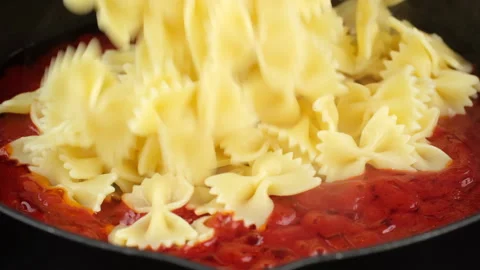 Putting pasta in pan with boiling tomato sauce, close up 스톡 동영상 246536004