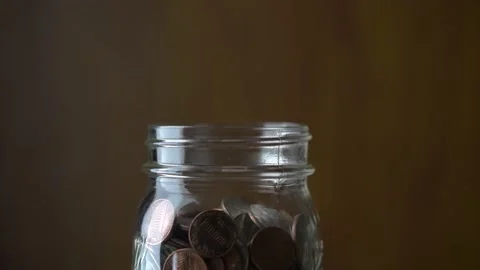 Putting penny in to jar, slow motion Stock Footage 157990632