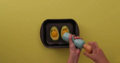 Putting pepper on the eggs and avocado 1 Vídeo Stock 132149579