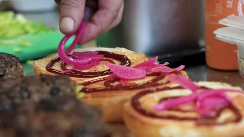 Putting pickled red onion on a burger Stock Footage 256078879