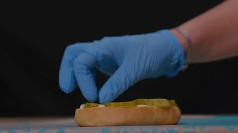 Putting Pickles On The Bun With Hands In Gloves 库存影片 221184928