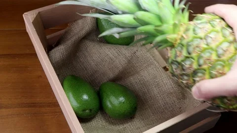 Putting pineapple in an avocado crate 스톡 동영상 184625501