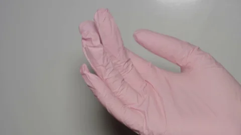 Putting on pink nitrile gloves on woman's hand. Close up Stock Footage 128446486
