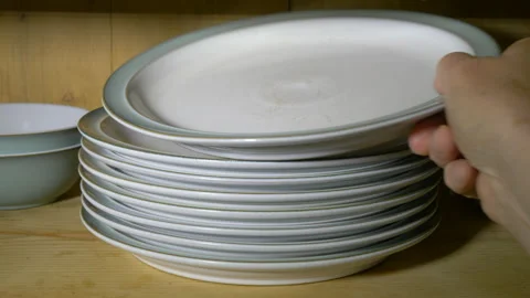 Putting plates into an old pine kitchen cupboard. Stock Footage 139698628